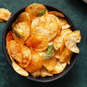 A bowl of spicy chips garnished with chili flakes and served with a side of dipping sauce.