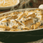 Garlic Parmesan Chicken Pasta Bake with golden cheese crust, tender chicken, and creamy sauce in a ceramic dish, garnished with parsley, served alongside garlic bread.