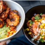 Grilled shrimp bowl with avocado, corn salsa, and creamy garlic sauce on a rustic table.