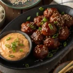 Korean BBQ meatballs served with spicy mayo dip on a wooden table.