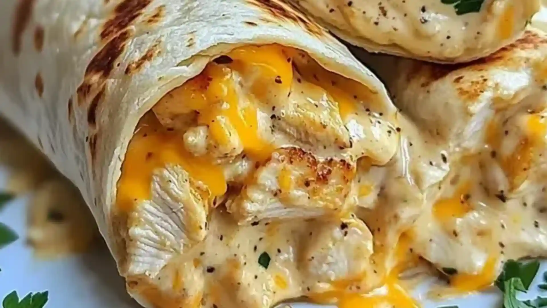 Golden cheesy chicken wrap cut open with gooey cheese and seasoned chicken, served with garlic sauce on a ceramic plate.