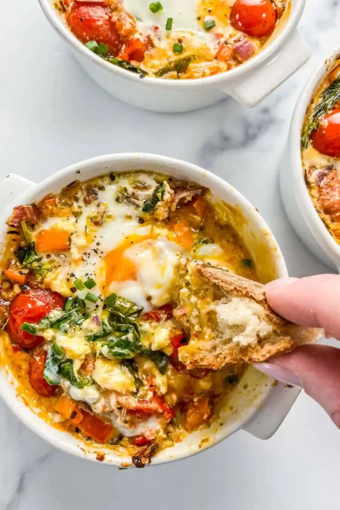 Close-up of baked feta eggs with soft yolk and herbs, set in a ramekin.

