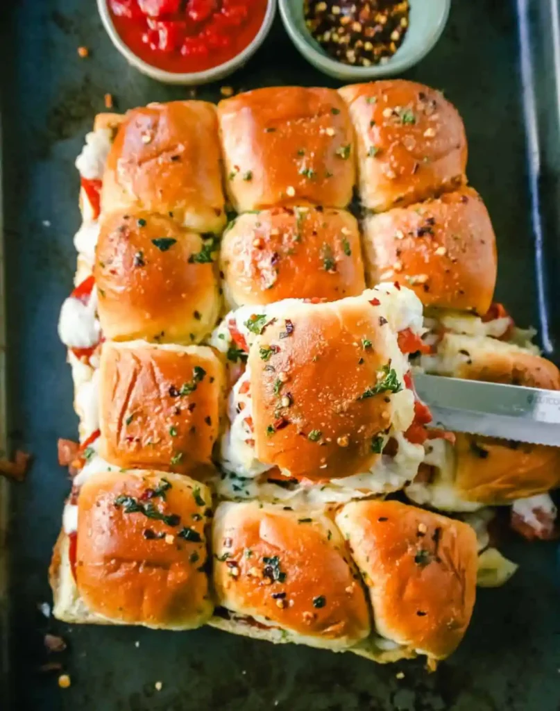 Platter of pizza sliders beside container of leftovers ready for storage.

