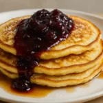 Fluffy lemon ricotta pancakes with cherry sauce butter and maple syrup on a rustic plate