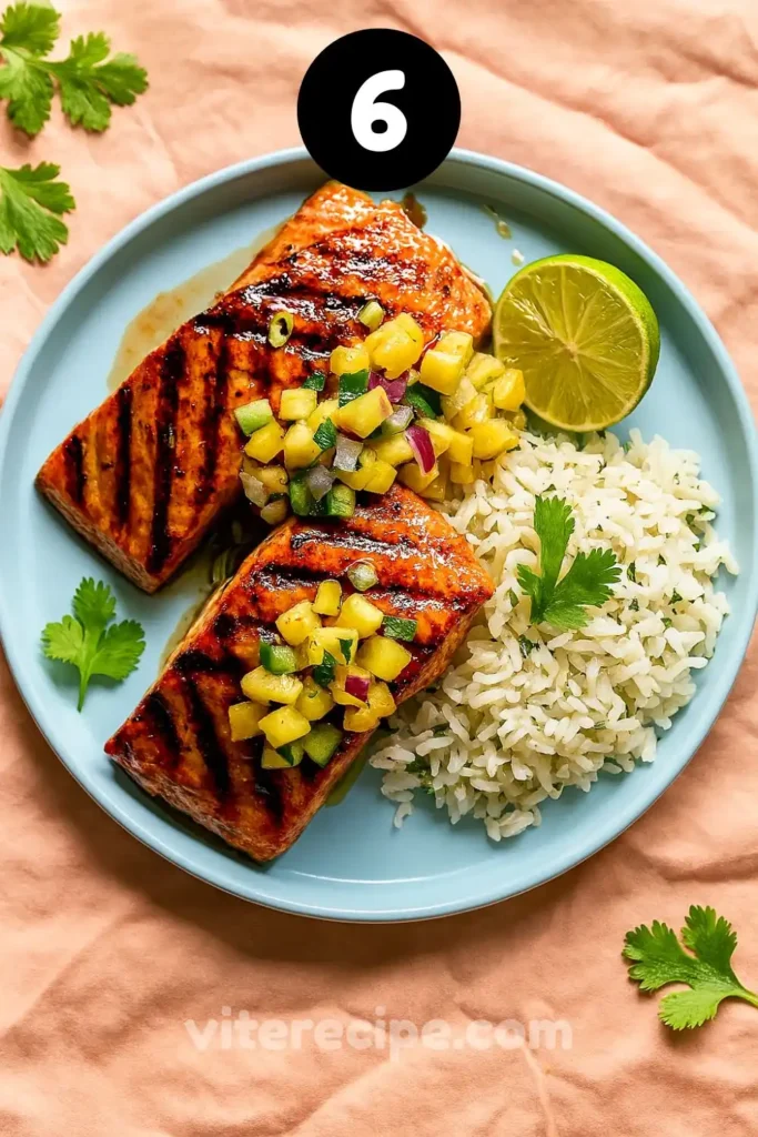 Grilled salmon topped with pineapple salsa and cilantro-lime rice on a white plate