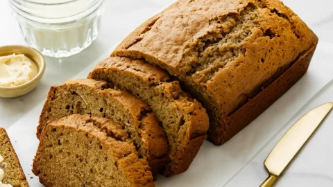 Freshly baked zucchini bread loaf sliced on a marble counter with butter and milk.