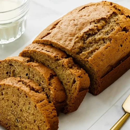 Freshly baked zucchini bread loaf sliced on a marble counter with butter and milk.