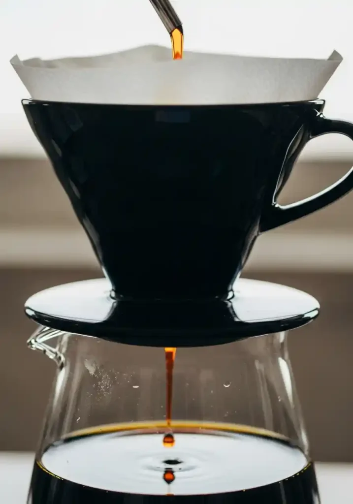 Close-up of cold brew liquid slowly dripping through a paper coffee filter set in a pour-over cone to achieve perfectly clear, sediment-free concentrate.