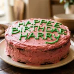 A pink frosted chocolate cake with green writing that says Happee Birthdae Harry, styled to look like Hagrid's cake from the movie.