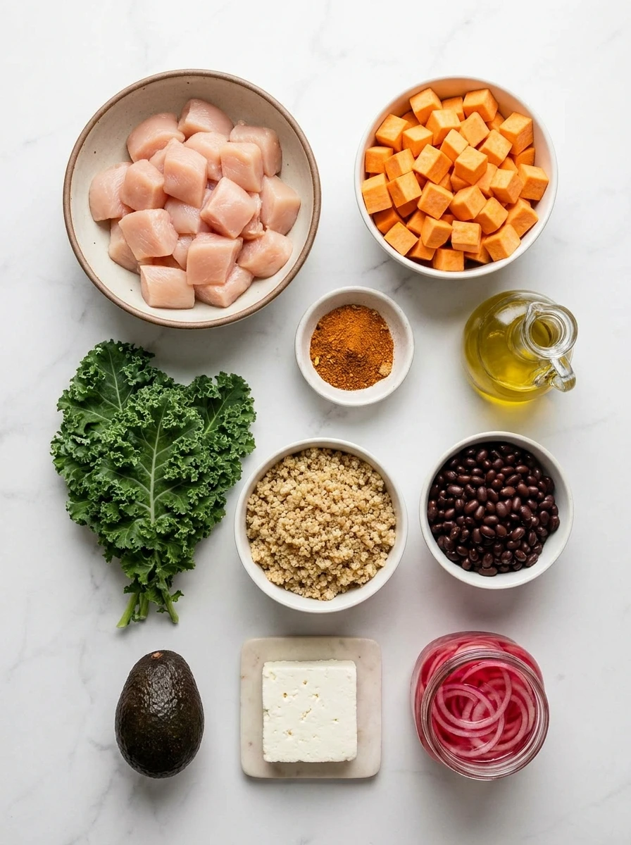 Sweet Potato And Chicken Bowls ,Top-down view of raw chicken, sweet potatoes, kale, black beans, and spices arranged on a marble surface.