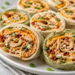Close-up of colorful chicken pinwheels made with flour and spinach tortillas, filled with shredded chicken, cheese, and buffalo sauce.