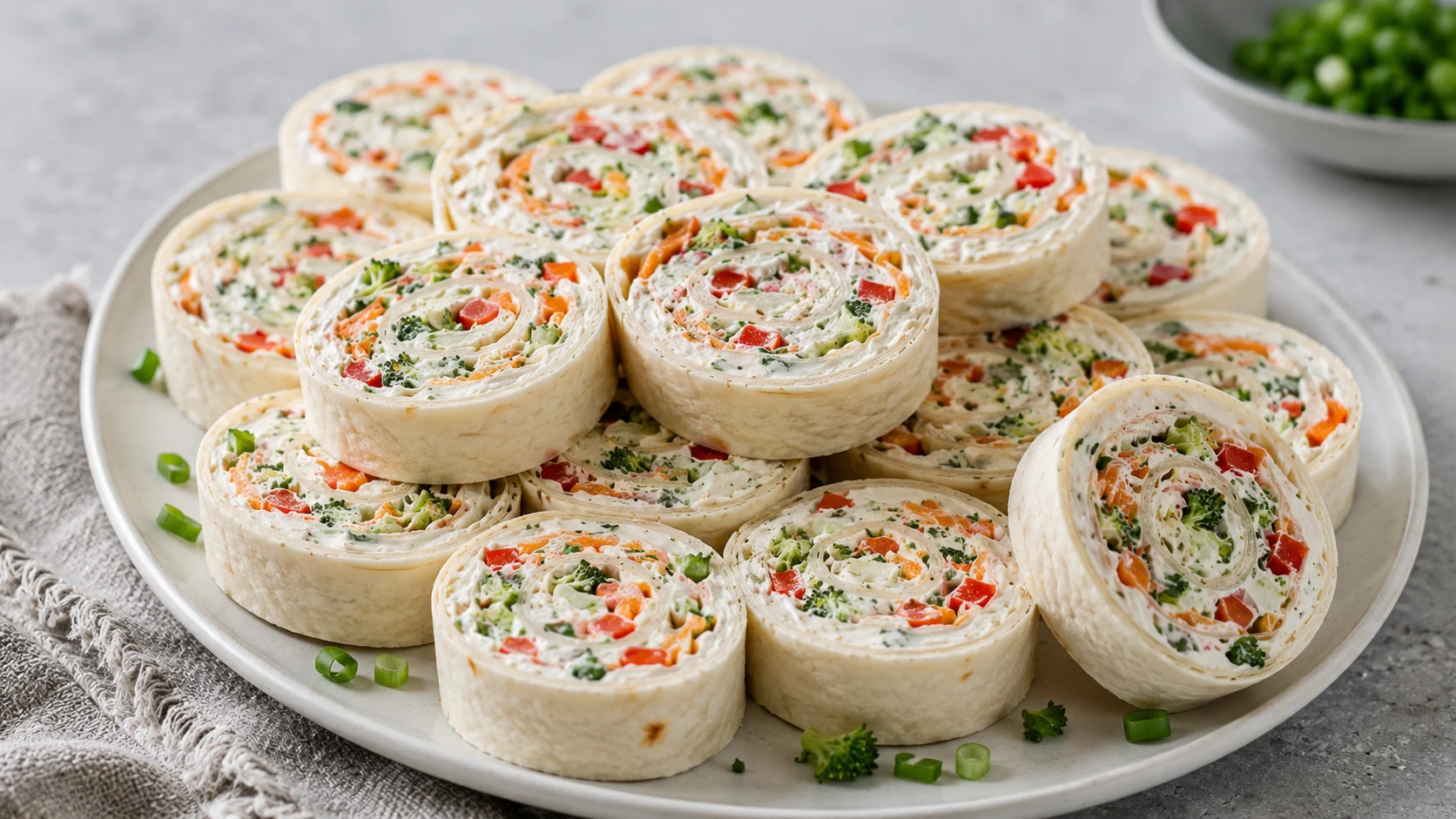 A close-up shot of several colorful veggie pinwheels featuring cream cheese, ranch seasoning, and fresh vegetables rolled in flour tortillas.