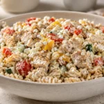 A vibrant high protein pasta salad with chickpea pasta, chicken, and fresh vegetables in a creamy dressing, served in a white bowl.