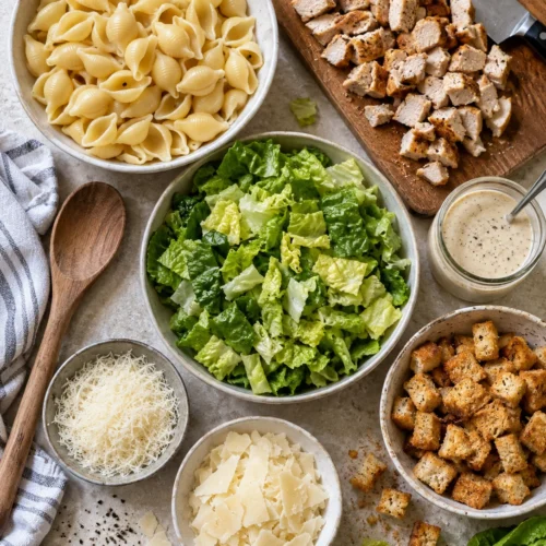A flat-lay of ingredients for the chicken caesar pasta salad