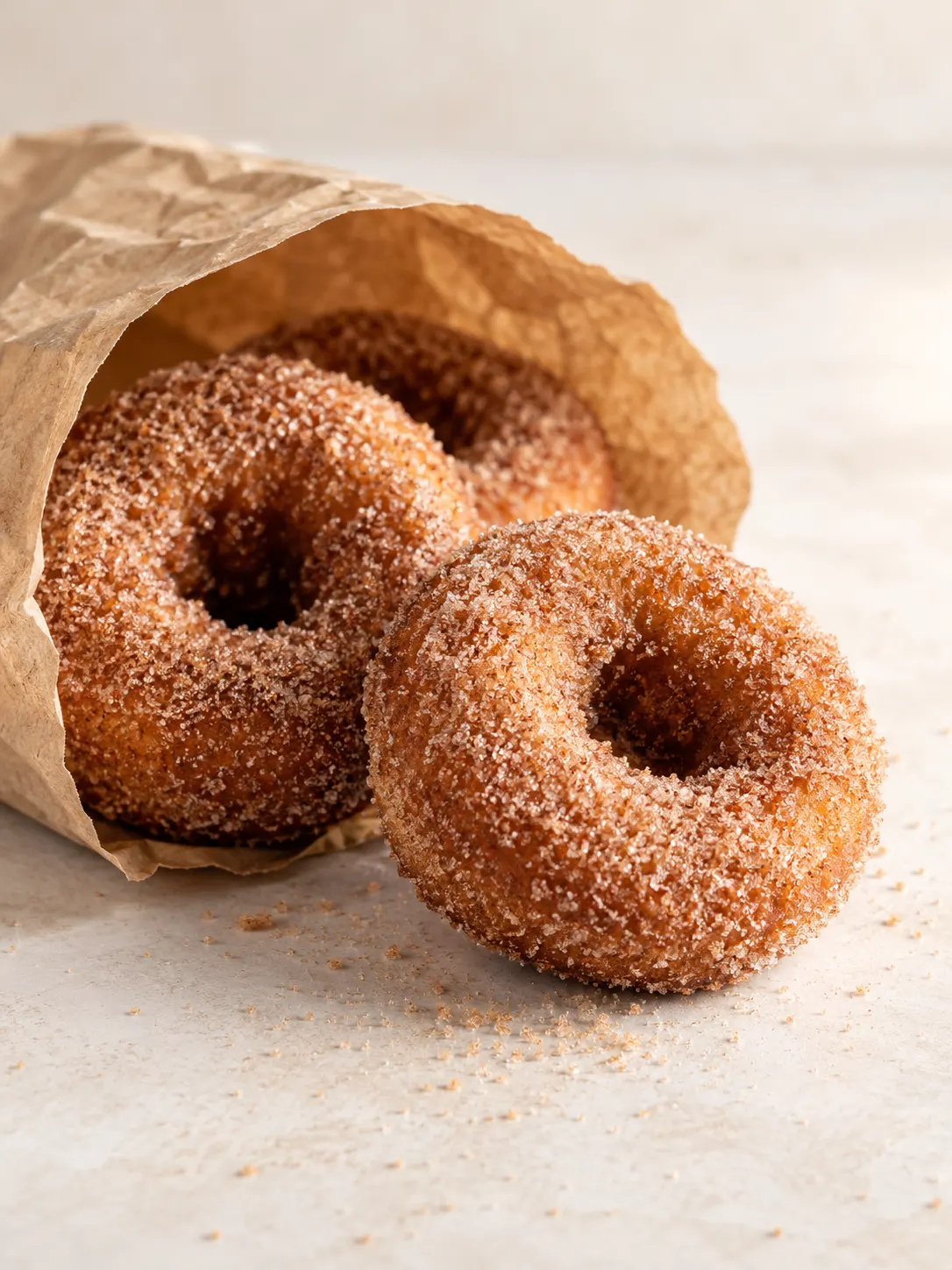 2-3 apple cider donuts in a paper bag or on a wire rack, on a neutral surface