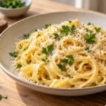 A serving of freshly cooked homemade fettuccine with parmesan cheese and parsley on a light wood kitchen table