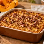 A freshly baked pumpkin baked oatmeal in a baking dish, topped with chopped pecans and a golden brown crust.